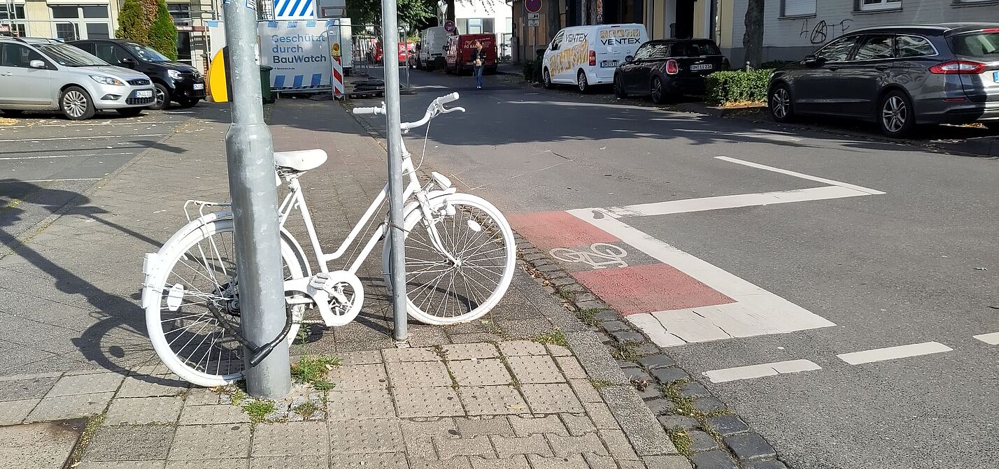 Ein weiß angemaltes Fahrrad an einem Laternenpfahl