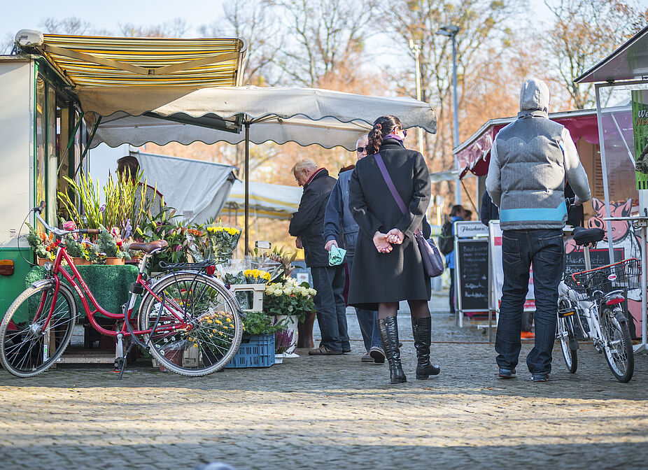 bv_Mit dem Rad zum Einkauf Marktszene mit Fußgängern und geparkten Fahrrädern